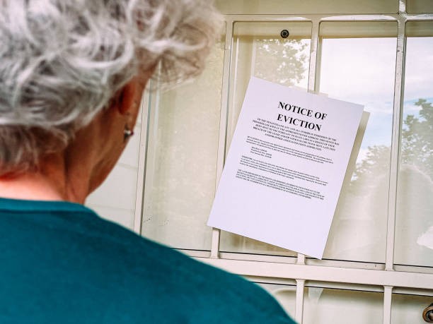 Tenant looking at a notice of eviction posted on a residential door, representing housing insecurity and the eviction process for renters.